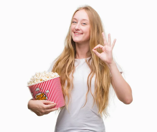 優秀なシンボルの指で サインをしてポップコーンを食べるブロンド十代の若者女性 — ストック写真