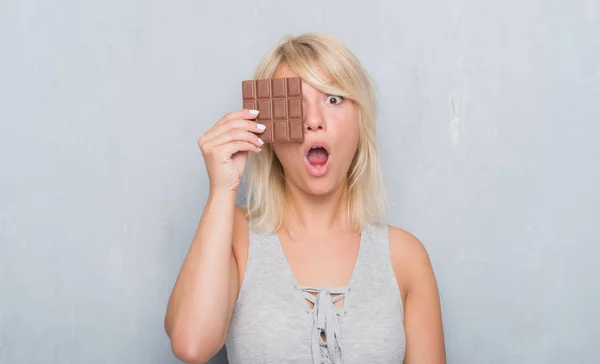 Caucásico Mujer Adulta Sobre Gris Grunge Pared Comer Chocolate Bar —  Fotos de Stock