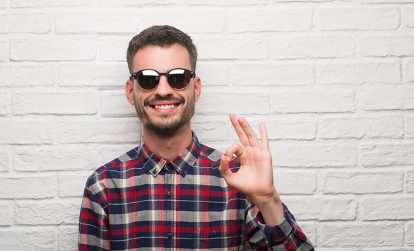 Jonge Volwassen Man Dragen Van Een Zonnebril Boven Witte Bakstenen — Stockfoto