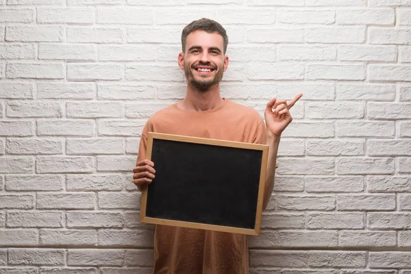 Blackboard Çok Mutlu Parmak Ile Tarafına Işaret Tutan Tuğla Duvarın — Stok fotoğraf