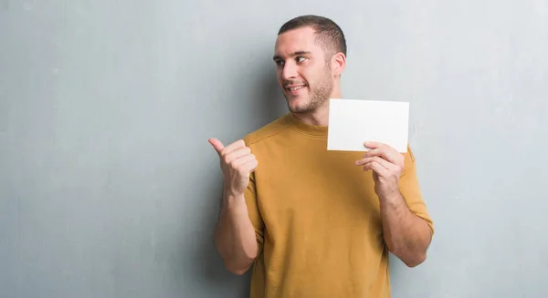 Joven Caucásico Hombre Sobre Gris Grunge Pared Celebración Tarjeta Blanco — Foto de Stock