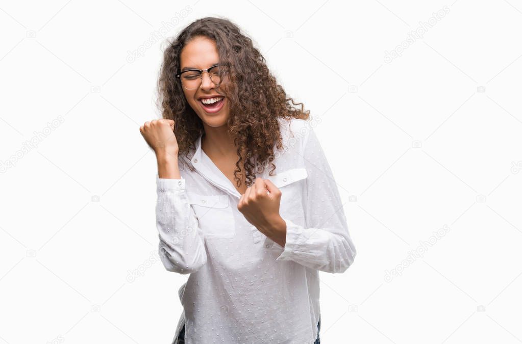 Beautiful young hispanic woman very happy and excited doing winner gesture with arms raised, smiling and screaming for success. Celebration concept.