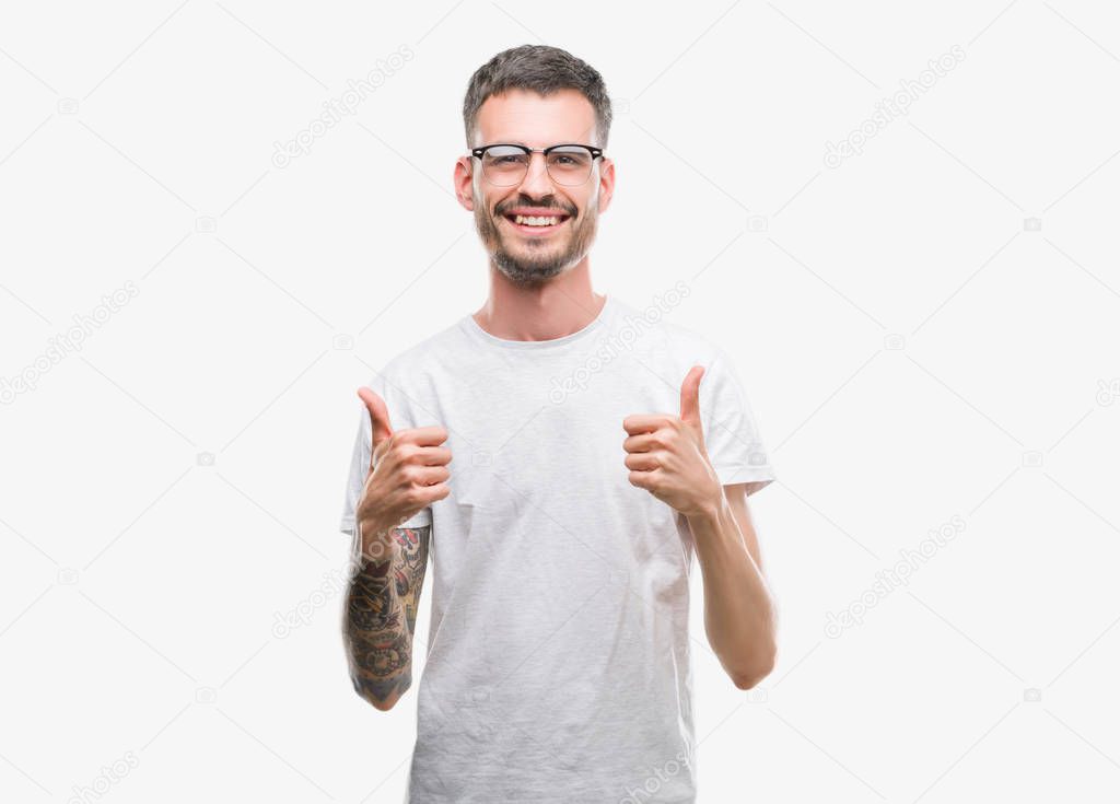 Young tattooed adult man success sign doing positive gesture with hand, thumbs up smiling and happy. Looking at the camera with cheerful expression, winner gesture.