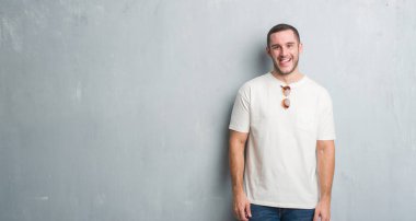 Beyaz delikanlı dilini güneş gözlüğü takıyor gri grunge duvarın üzerinden out komik ifade ile mutlu. Duygu kavramı.