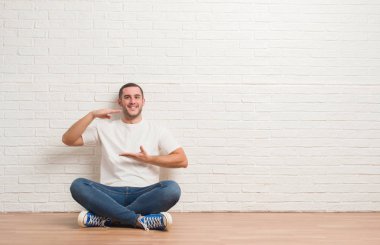 Beyaz tuğla duvar eller eller büyük gösterilen ve büyük boy işareti, ölçü birimi sembolü ile üzerinden katta oturan beyaz delikanlı. Kameraya bakarak gülümsüyordu. Ölçüm kavramı.