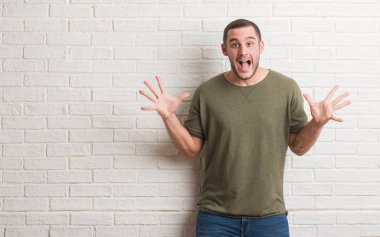 Beyaz tuğla duvar kaldırdı kollarını açarak deli ve başarı için hayran kutluyor ve açık gözleri heyecanlı çığlık üzerinde duran beyaz delikanlı. Kazanan kavramı