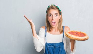 Grunge güzel genç kadın gri duvar büyük gülümseme ile çığlık ve ellerini kaldırdı kazanan ifade kutluyor zafer pepperoni pizza çok mutlu ve heyecanlı, yemek