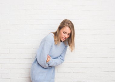 Güzel genç kadın yüzünden beyaz tuğla duvar mide üzerinde el ile Çünkü mide bulantısı, ağrılı hastalık hasta hissediyor. Ağrısı kavramı.
