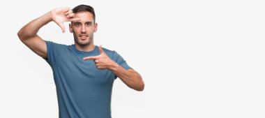 Elle yapma çerçeve ve parmakları ile mutlu yüz gülümseyen yakışıklı genç casual adam. Yaratıcılık ve Fotoğrafçılık kavramı.