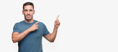 Gülümseyen ve iki ile işaret kamera bakarak rahat yakışıklı genç eller ve yan parmak.