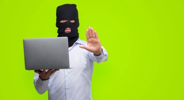 Hacker işadamı ile bir bilgisayar dizüstü bilgisayar tutarak açık el dur işareti ile ciddi ve kendine güvenen ifade, savunma hareketi yapıyor