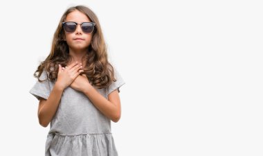 Esmer Latin kız ile gülümseyen güneş gözlüğü takıyor kapalı gözler ve yüzünde minnettar jest ile göğüs üzerinde eller. Sağlık kavramı.