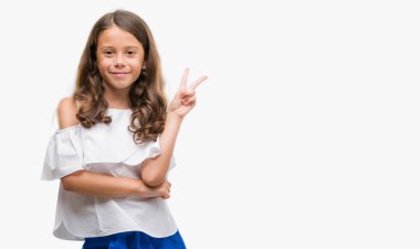 Esmer Latin kız mutlu yüz zafer işareti yaparken kameraya göz kırpıyor ile gülümseyen. İki numaralı.