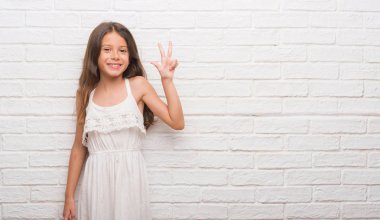 Genç İspanyol çocuğun gösterilen ve parmakları ile işaret beyaz tuğla duvarın üzerinden üçüncü ise kendinden emin ve mutlu gülümseyerek.