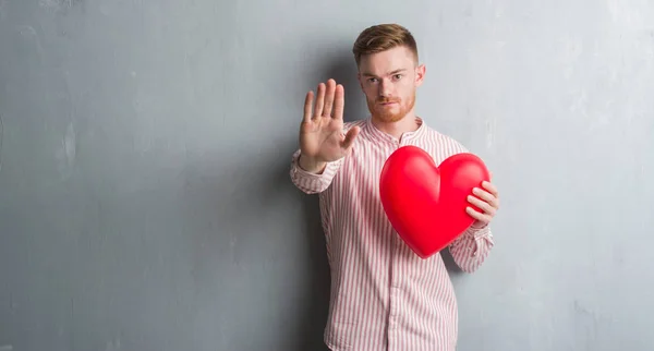 Joven Pelirrojo Sobre Pared Gris Grunge Sosteniendo Corazón Rojo Con — Foto de Stock