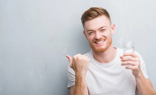 Joven Pelirrojo Hombre Sobre Gris Grunge Pared Beber Agua Apuntando — Foto de Stock