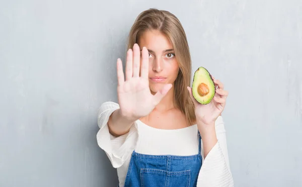 Beautiful Young Woman Grunge Grey Wall Eating Avocado Open Hand — Stock Photo, Image