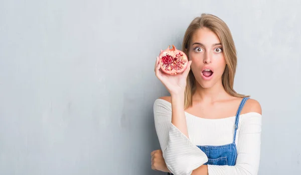 Vacker Ung Kvinna Över Grunge Grå Väggen Hålla Granatäpple Rädd — Stockfoto