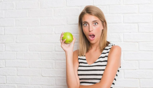 Beyaz Tuğla Duvar Yeme Üzerinde Güzel Genç Kadın Yeşil Elma — Stok fotoğraf