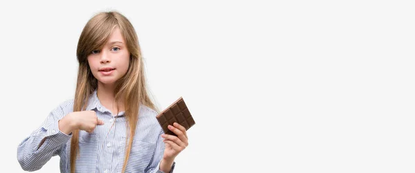Young Blonde Child Holding Chocolate Bar Surprise Face Pointing Finger — Stock Photo, Image