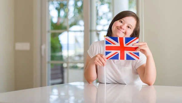 唐氏综合症妇女在家里持有英国国旗与一个幸福的脸站在微笑着自信的微笑显示牙齿 — 图库照片