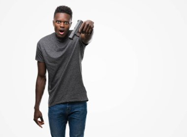 Elinde bir silah bir sürpriz yüz, korkuyor ve heyecanlı korku ifadesi ile şok korkmuş genç Afro-Amerikan adam
