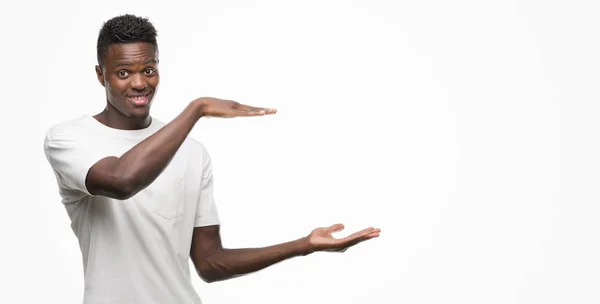 若いアフリカ系アメリカ人メジャー シンボル兆し大きな 大きなサイズの手でジェスチャー白い シャツを身に着けています カメラを見て笑っています 測定概念 — ストック写真