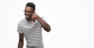 Gözlük ve Donanma gülümseyen t-shirt giyen genç Afro-Amerikan adam el ve parmak telefonda konuşmak ile telefon jest yapıyor. Kavramları iletişim.