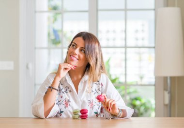 Soru hakkında çok düşünüyorum ev yeme macarons ciddi bir yüz genç kadına fikir karışık