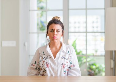 Genç kadın evde komik surat ile yanakları şişirme. Ağız ile hava, deli ifade şişirilmiş.