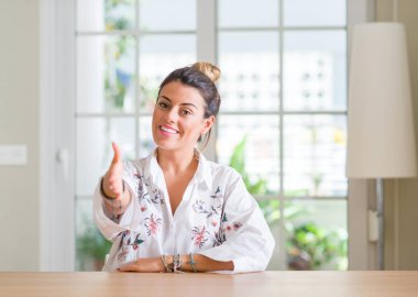 Tebrik ve konuksever dost sunan karşılıklı gülümseyen genç kadın evde. Başarılı iş.