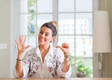 Genç kadın evde gösterilen ve parmak altıncı ile gülümseyen ise kendinden emin ve mutlu yukarı dönük.