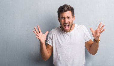 Gri grunge duvar kutluyor üzerinden yakışıklı genç adam kızgın ve silah ile başarı için deli kaldırdı ve heyecanlı çığlık gözler kapalı. Kazanan kavramı