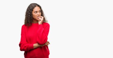 Stresli ve gergin ile kırmızı kazak giyen genç İspanyol kadın tırnak ısırma dudaklarından eller. Anksiyete sorunu.