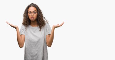 Gözlük clueless ve şaşkın bir ifadeyle kollar ve eller kaldırdı giyen güzel genç İspanyol kadın. Şüphe kavramı.