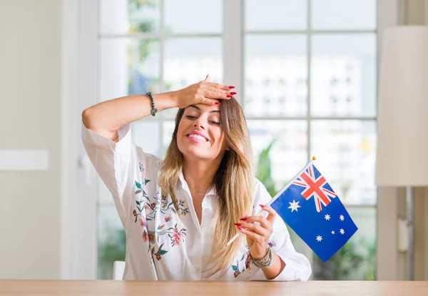 Young woman at home holding flag of Australia stressed with hand on head, shocked with shame and surprise face, angry and frustrated. Fear and upset for mistake.
