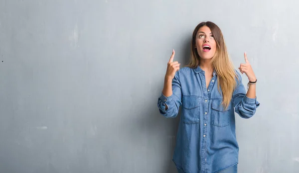 Junge Erwachsene Frau Über Grunge Grauer Wand Jeans Outfit Erstaunt — Stockfoto