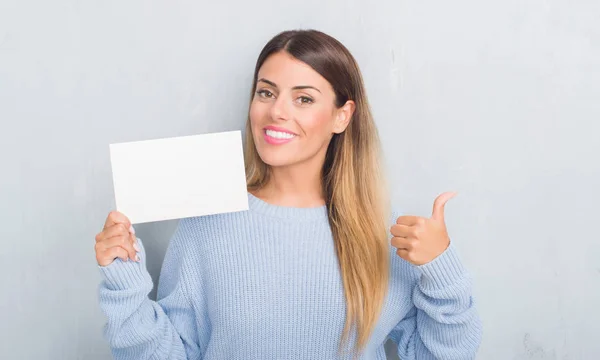 Joven Mujer Adulta Sobre Pared Grunge Gris Sosteniendo Tarjeta Blanco —  Fotos de Stock