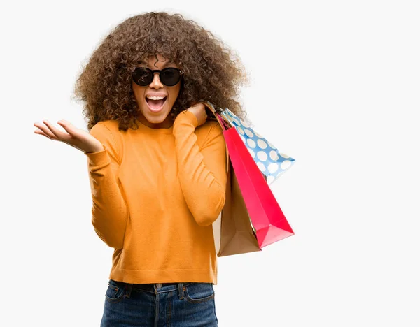 叫んで笑顔で勝利を祝って 手を上げたショッピング バッグ非常に幸せと興奮 勝者式を保持しているアフリカ系アメリカ人の女性 — ストック写真