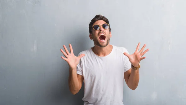 Joven Guapo Sobre Una Pared Grunge Gris Con Gafas Sol — Foto de Stock