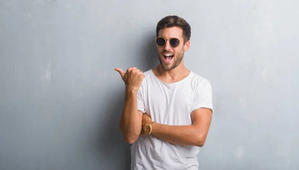 Guapo Joven Sobre Gris Pared Grunge Usando Gafas Sol Sonriendo — Foto de Stock