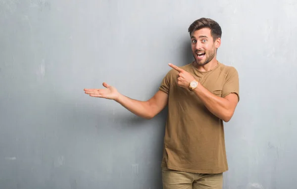 Jovem Bonito Sobre Parede Grunge Cinza Espantado Sorrindo Para Câmera — Fotografia de Stock