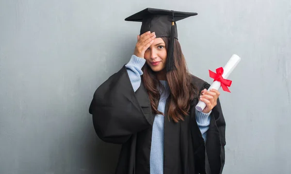 Joven Morena Sobre Pared Gris Grunge Con Uniforme Graduado Sosteniendo — Foto de Stock