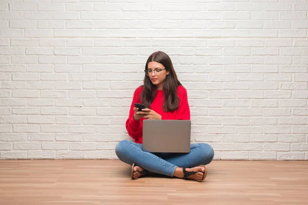 Mujer Morena Joven Sentada Suelo Usando Ordenador Portátil Teléfono Inteligente —  Fotos de Stock