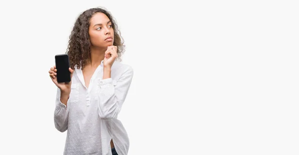 Young Hispanic Woman Using Smartphone Serious Face Thinking Question Very — Stock Photo, Image