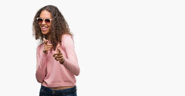 美しい若いヒスパニック系女性の幸せと面白い顔でカメラに指を指してサングラスを身に着けています 良いエネルギーとヴァイブス — ストック写真