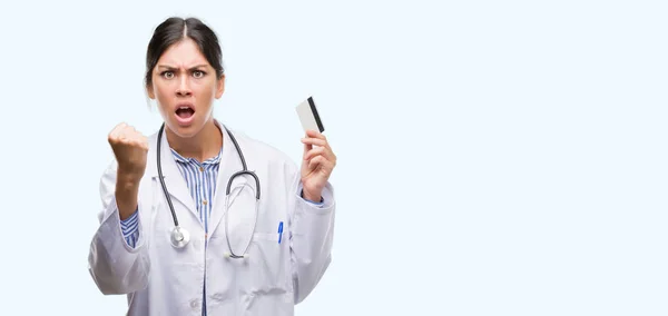 Young Hispanic Doctor Woman Holding Credit Card Annoyed Frustrated Shouting — Stock Photo, Image