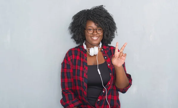 Unga Afroamerikanska Kvinnan Över Grå Grunge Vägg Bär Hörlurar Leende — Stockfoto