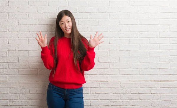 Genç Çinli Kadın Gösterilen Parmakları Ile Işaret Tuğla Duvarın Üzerinden — Stok fotoğraf
