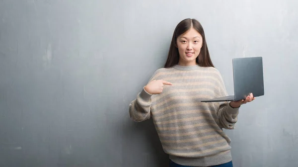 Молодая Китаянка Перелезает Через Серую Стену Используя Ноутбук Неожиданным Лицом — стоковое фото